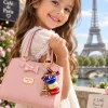Little girl holding a pink handbag with Eiffel Tower macaron keyring and French flag bow